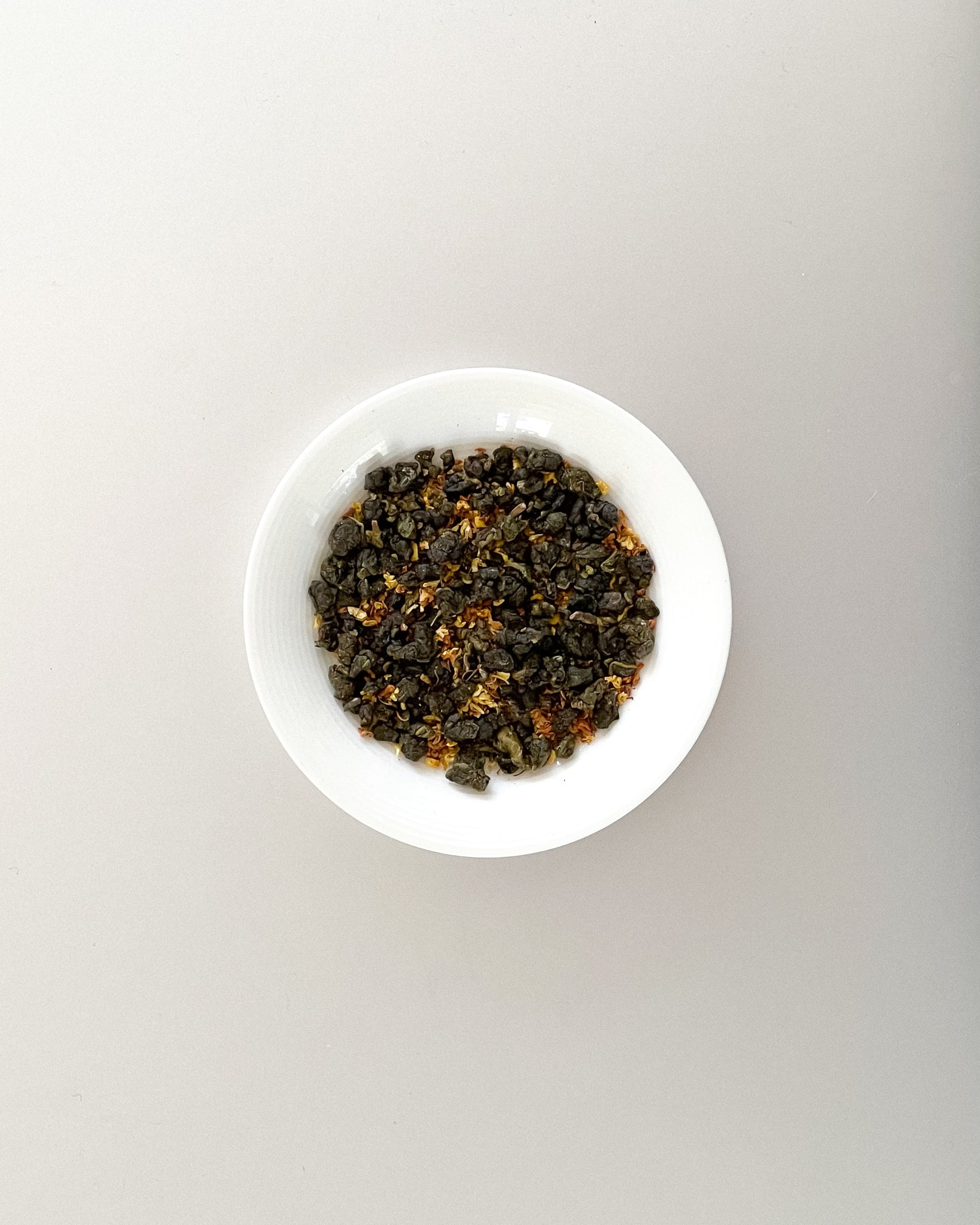 Teappo Osmanthus Oolong tea leaves displayed in a clear container, showcasing the delicate, fragrant tea.