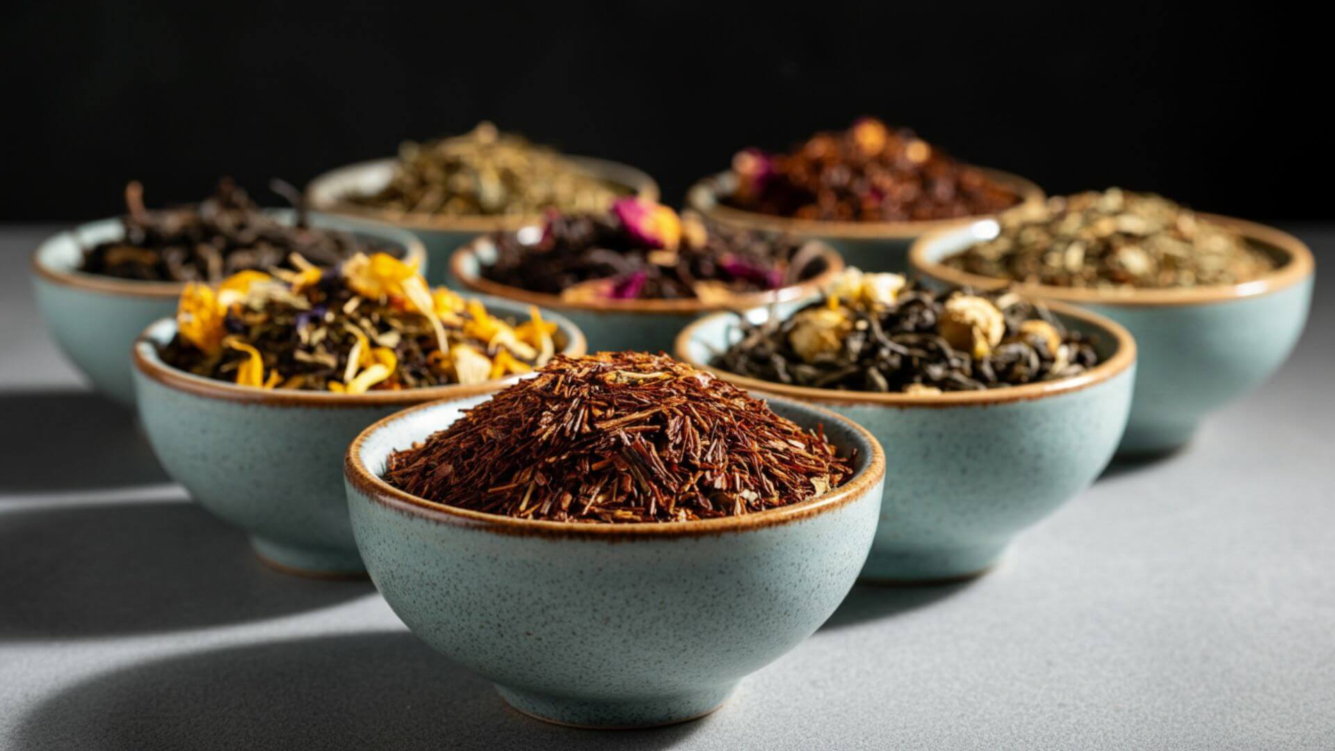 Seven bowls filled with assorted herbal leaf teas