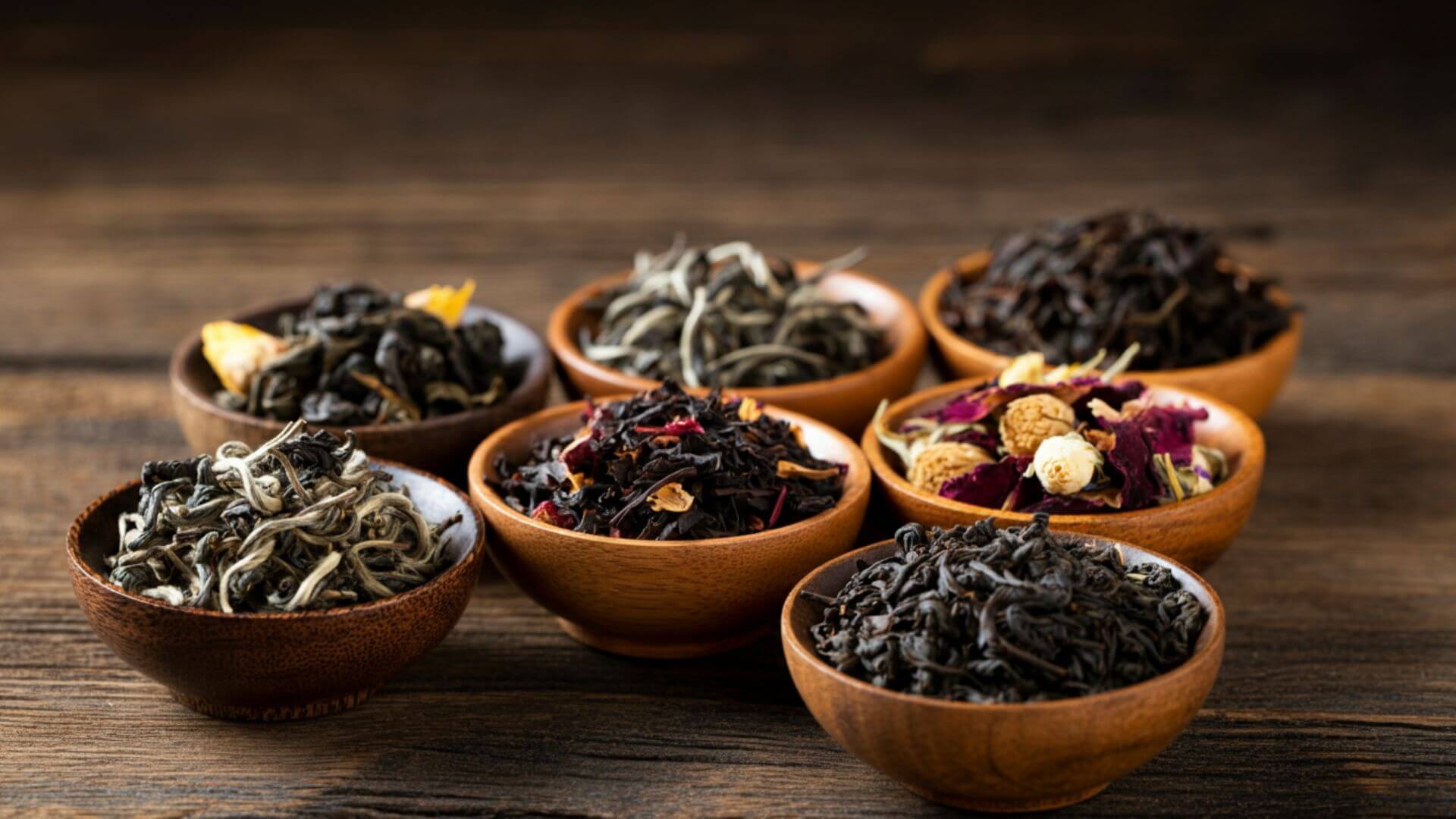 A collection of wooden bowls filled with various loose leaf teas