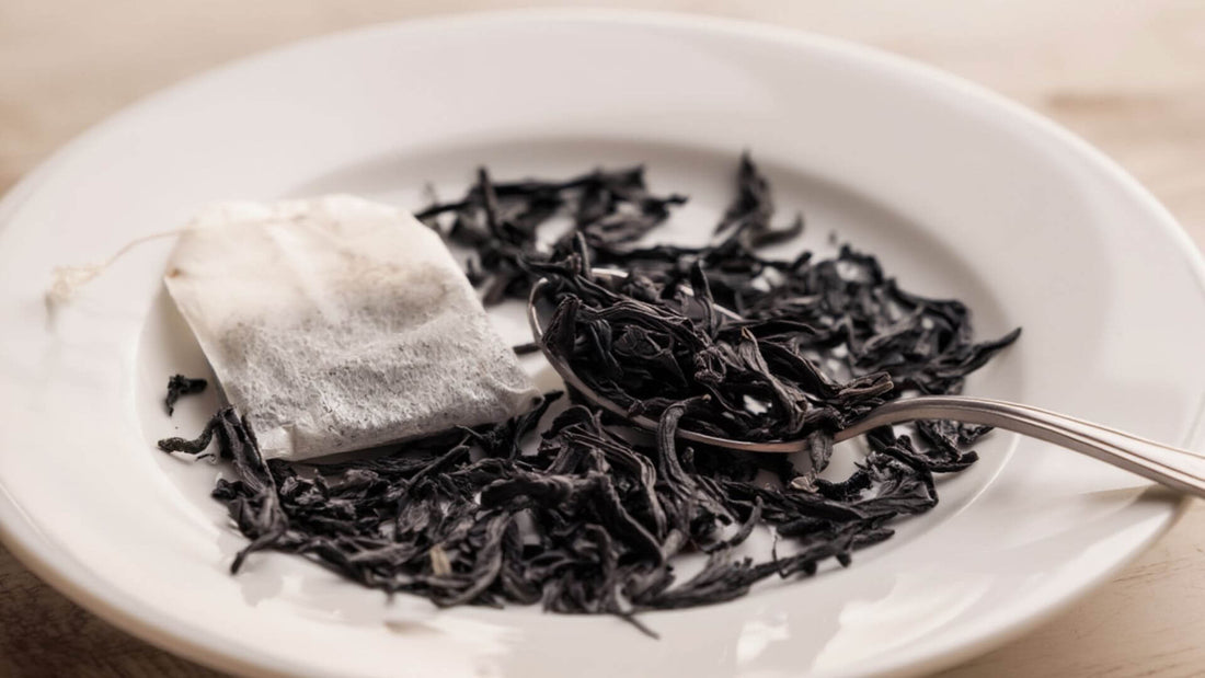 Loose leaf black teas in a plate with silver spoon and teabag