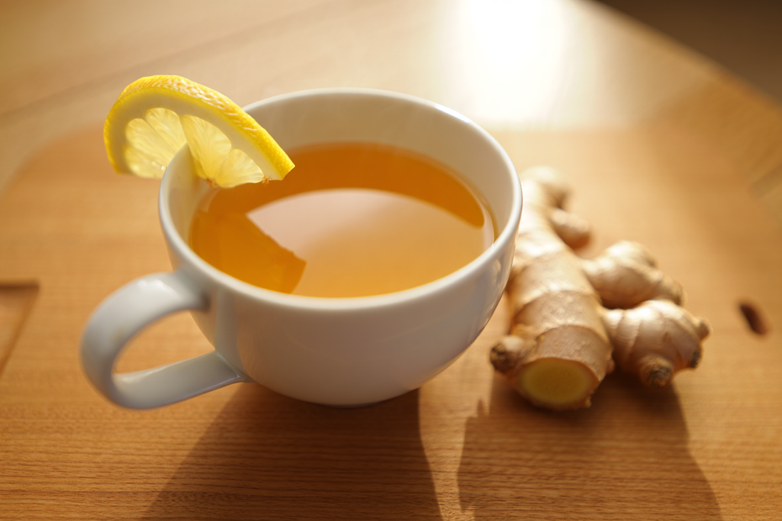 A mug of golden ginger tea with lemon and fresh ginger root