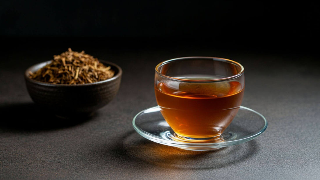 A glass cup filled with hojicha tea in a saucer, in the background features hojicha in a bowl