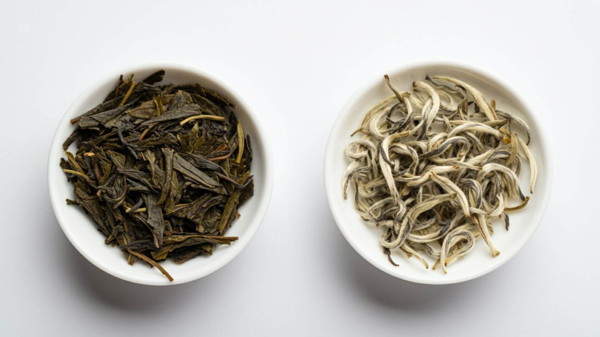 Two white ceramic bowls each containing a loose leaf green and white tea