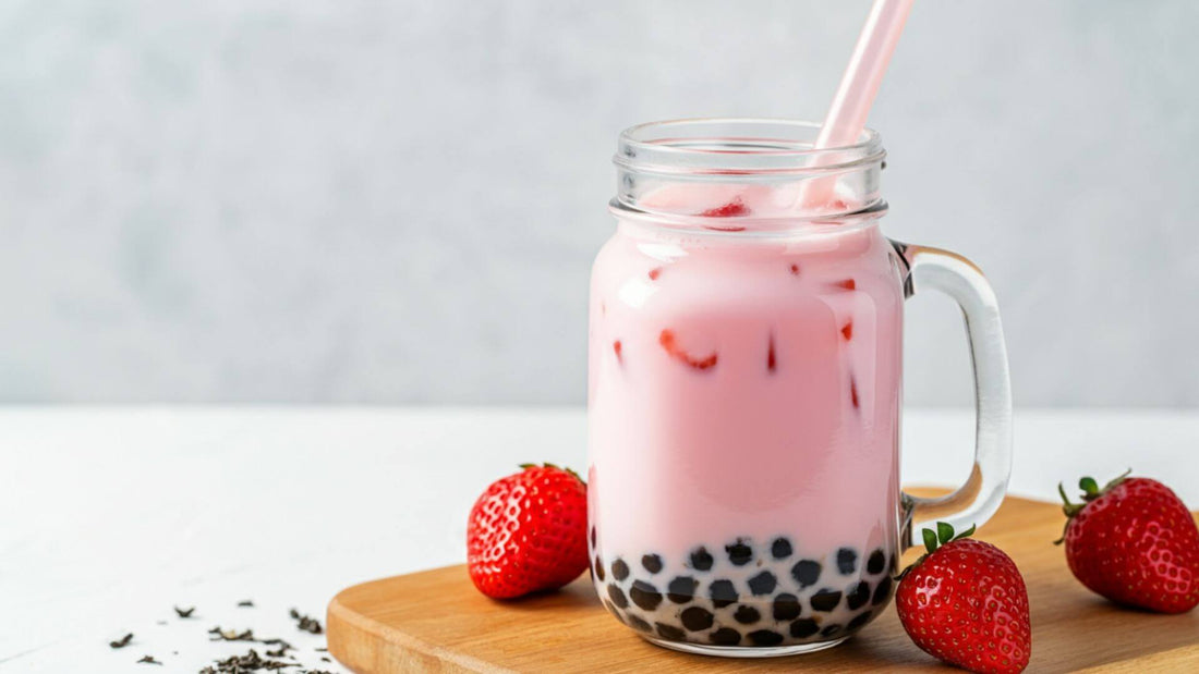 A glass mason jar filled with strawberry milk tea, with black tapioca pearls settled at the bottom