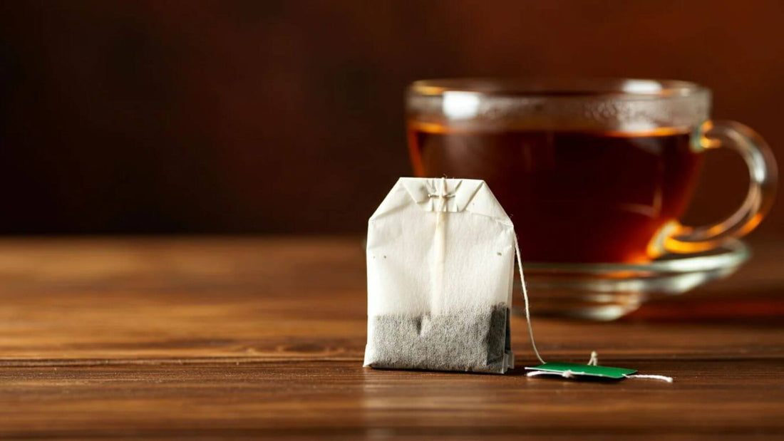 A tea bag with a cup of tea in the background