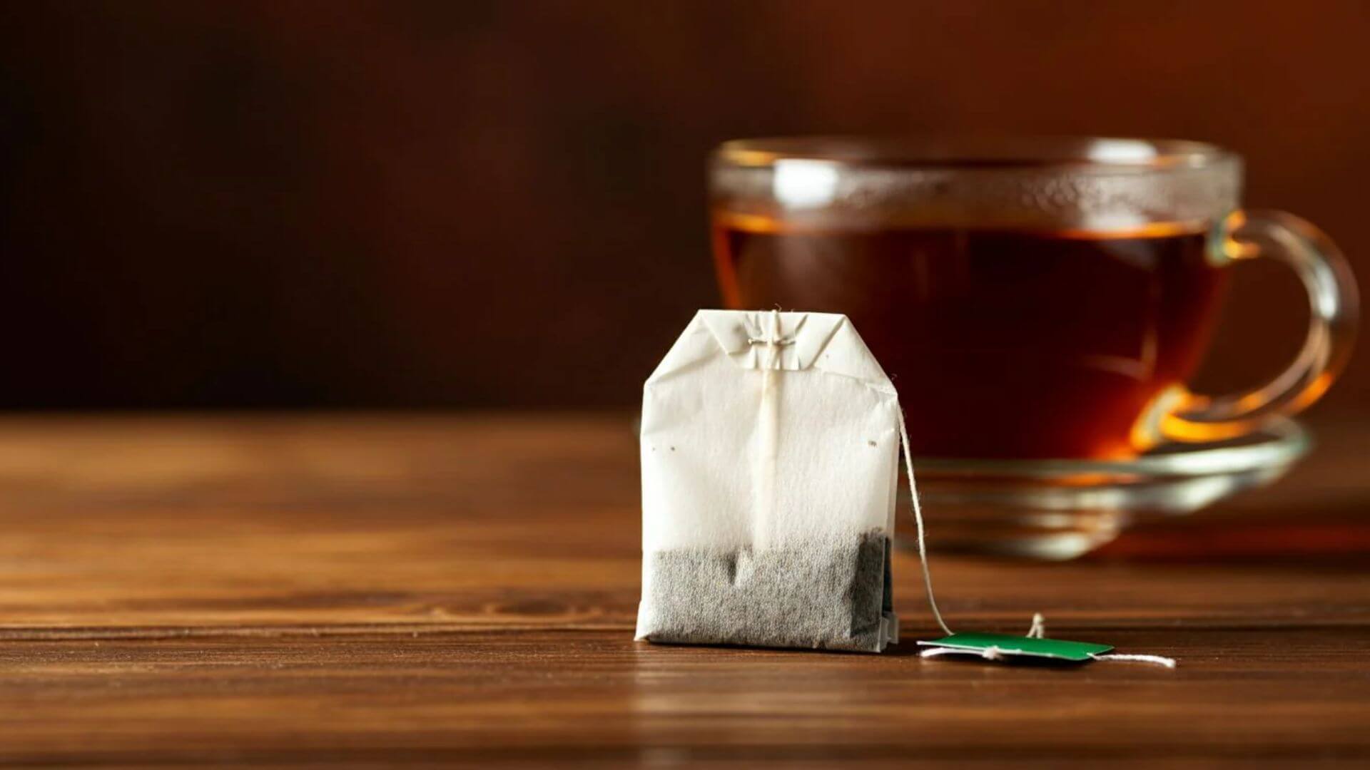 A tea bag with a cup of tea in the background