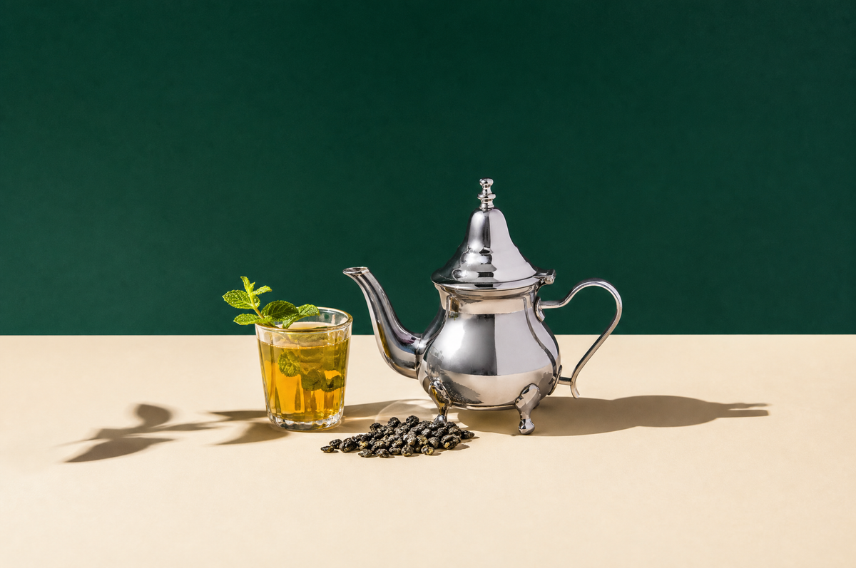 A plain polished silver-toned Moroccan-style metal teapot with a long curved spout