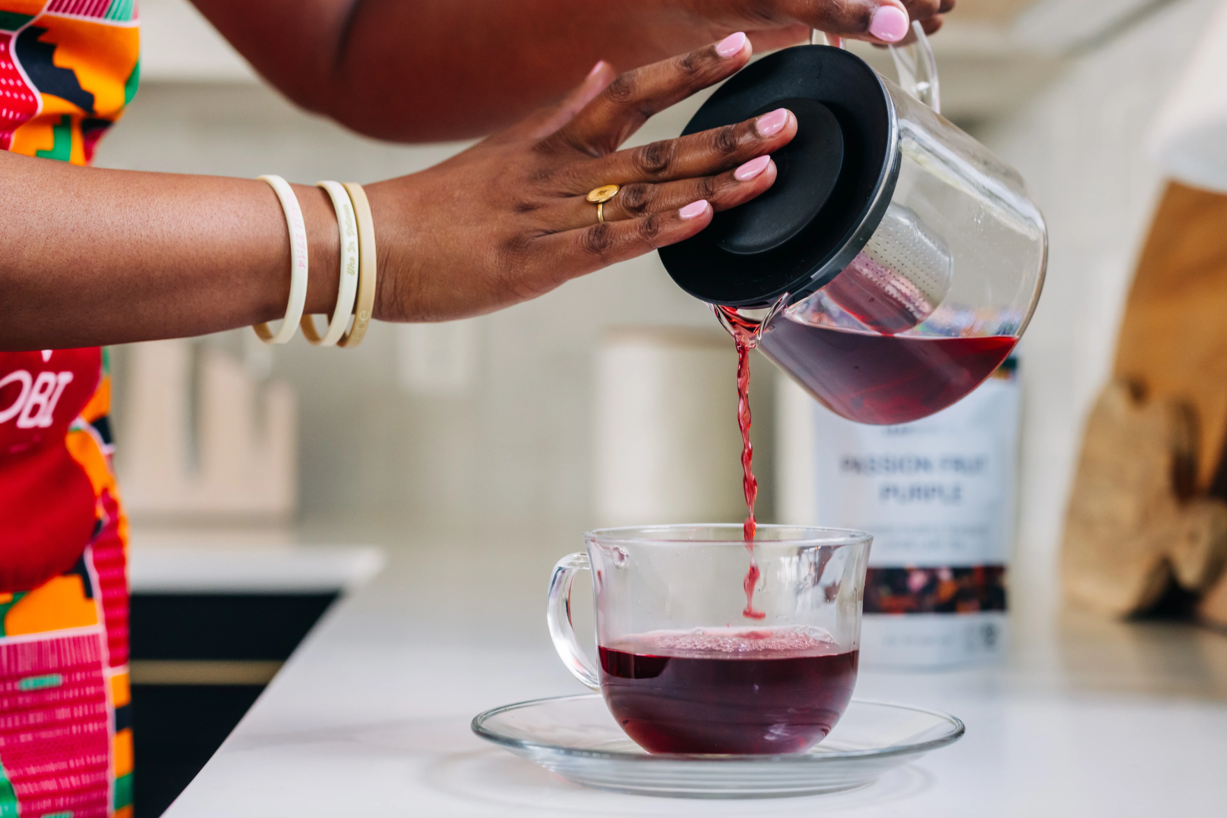 a woman pouring leafberri tea to a glass cup