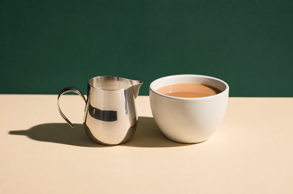 A small polished stainless steel milk jug with a pouring spout and a single curved handle