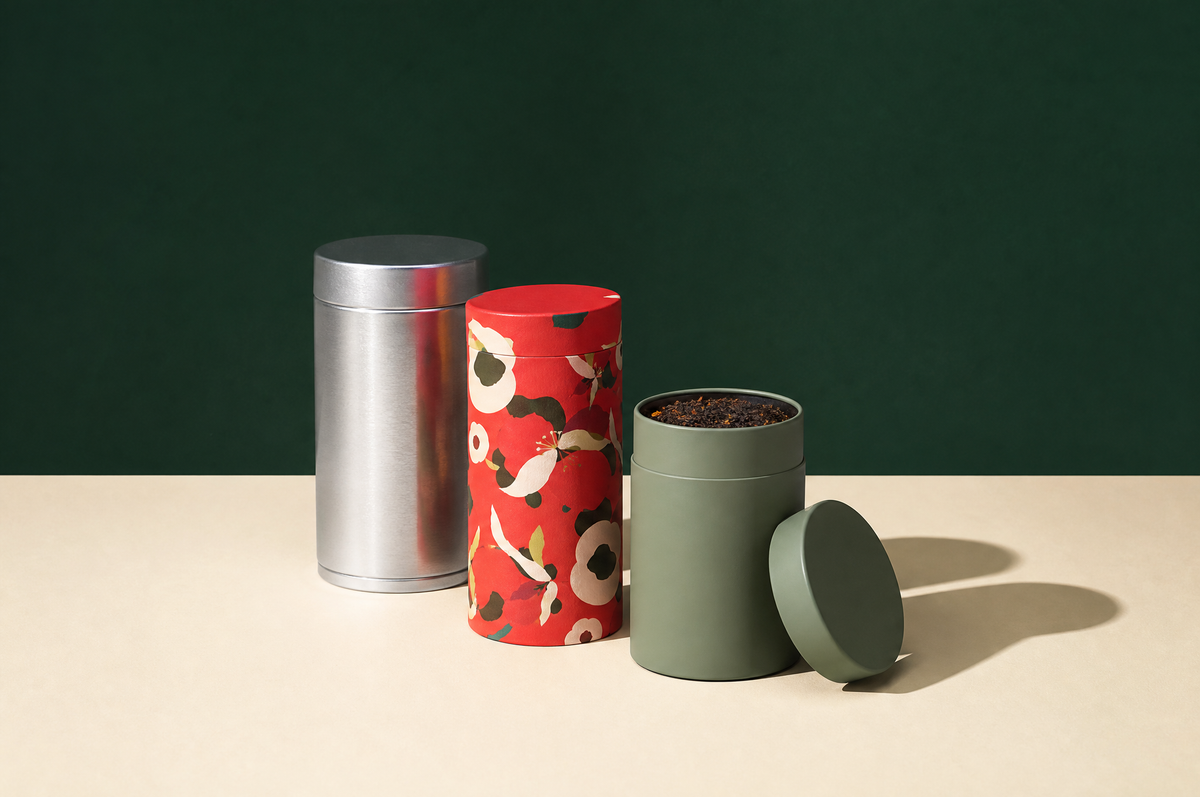Three cylindrical tea canisters of different heights: a brushed silver tin