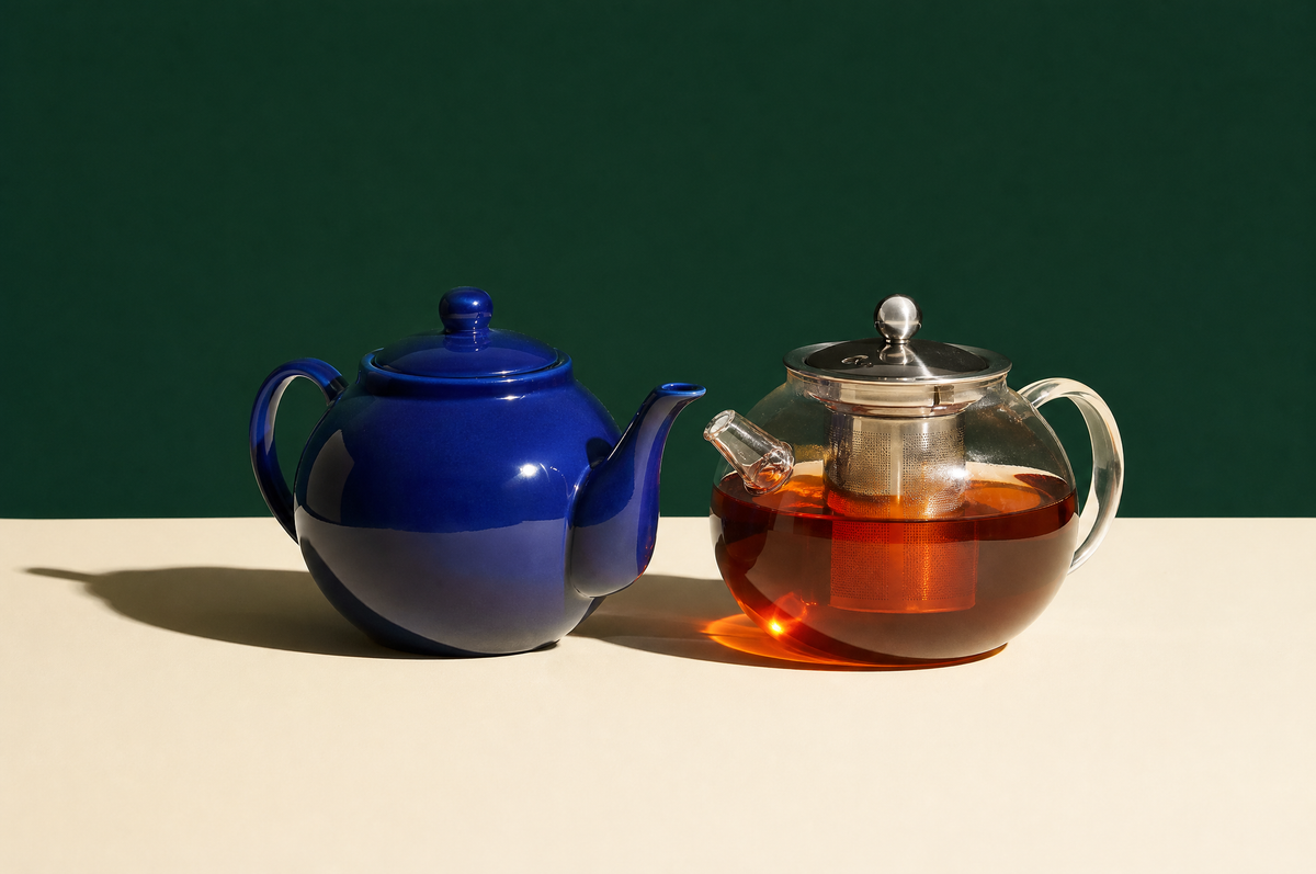 A round glossy cobalt-blue ceramic teapot with a curved spout and a loop handle