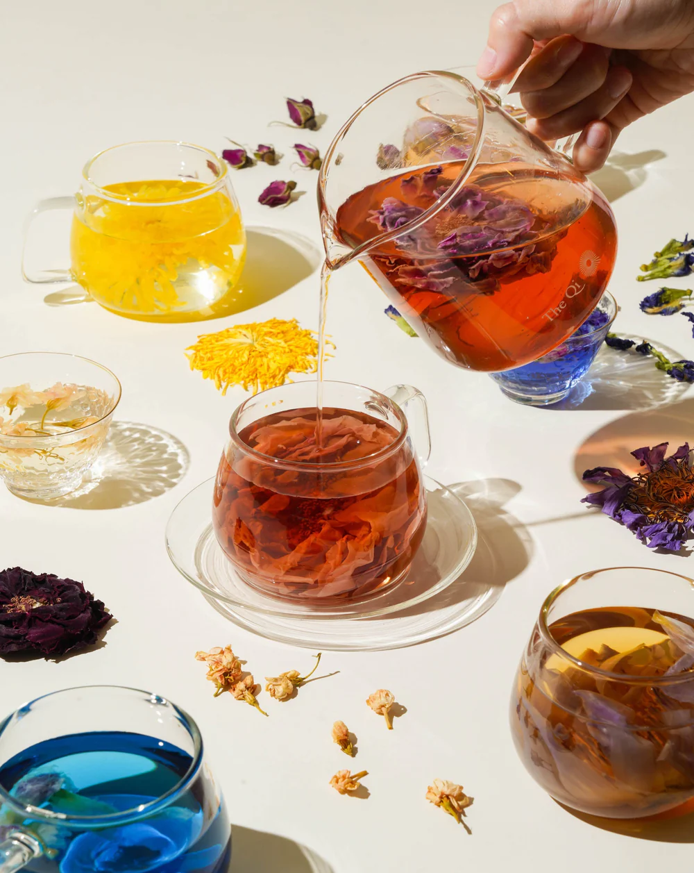 flower teas in glass pitcher is being poured down to a glass cup