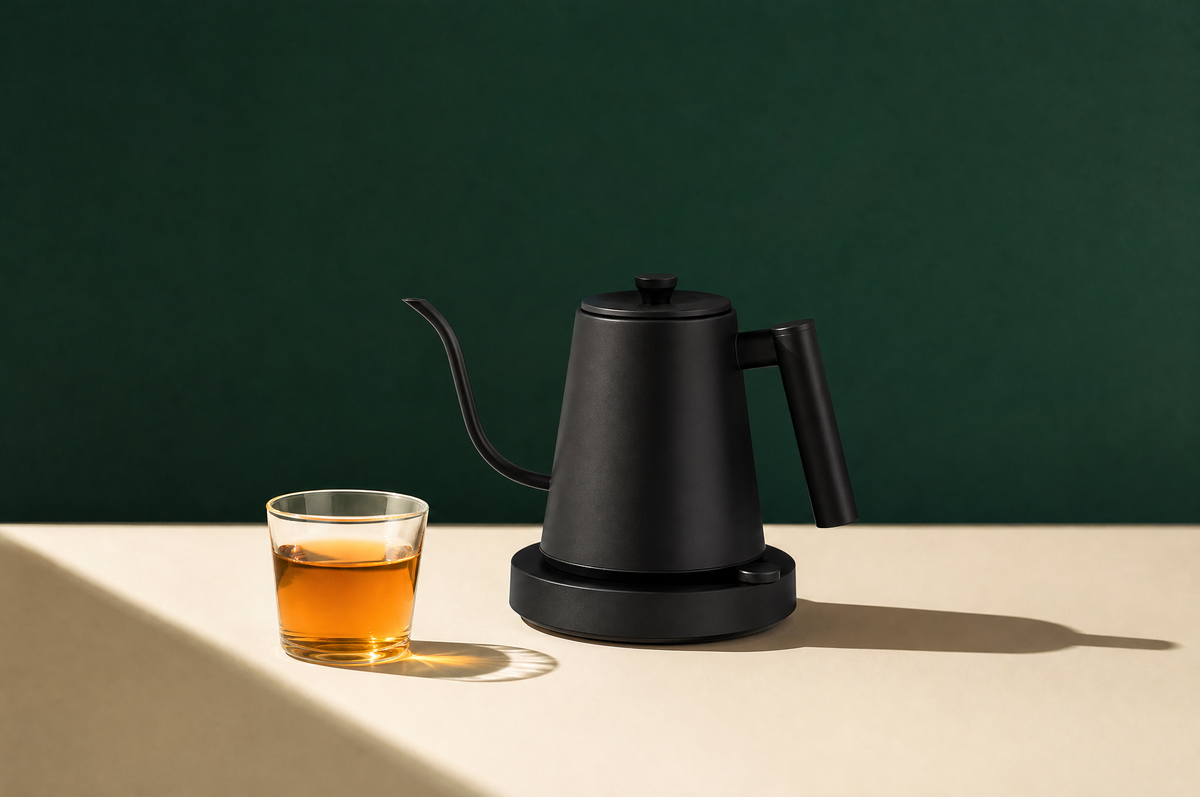 A matte black stainless steel gooseneck electric kettle with a slim curved spout and a plain round power base with no