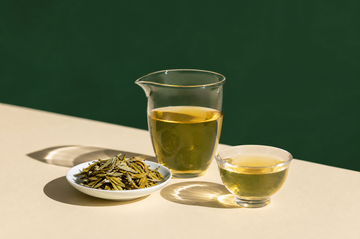 A small clear glass fairness pitcher of pale golden-yellow tea and a small clear glass cup of the same tea