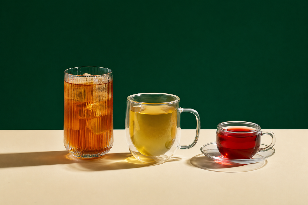 Three clear glass drinking vessels in a row, each a different shape: a tall ribbed iced-tea glass of amber tea with ice