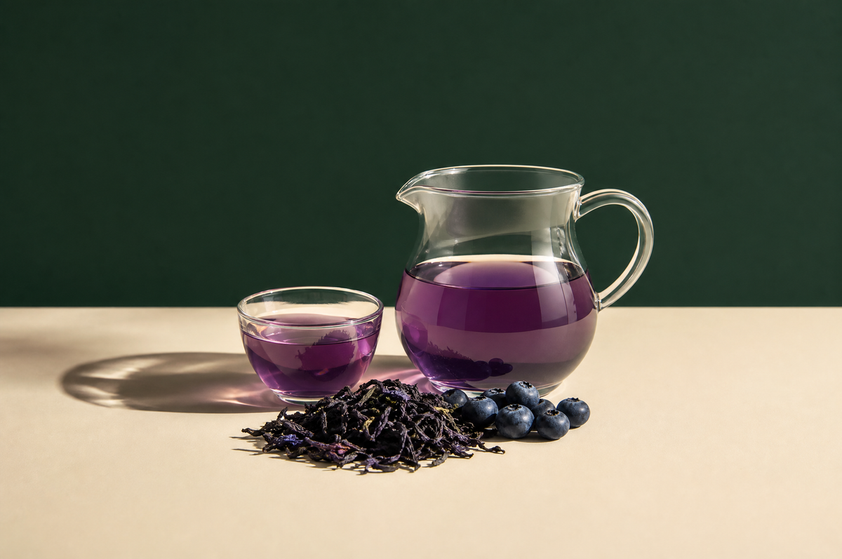 A clear glass pitcher and a small clear glass cup, both filled with soft violet-purple tea