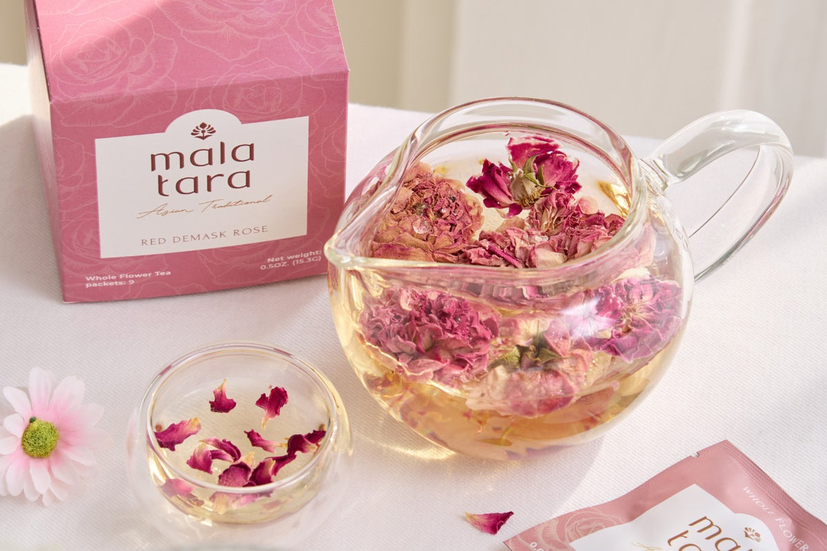 Mala Tara Red Damask Rose tea box beside a glass teapot of whole rose buds