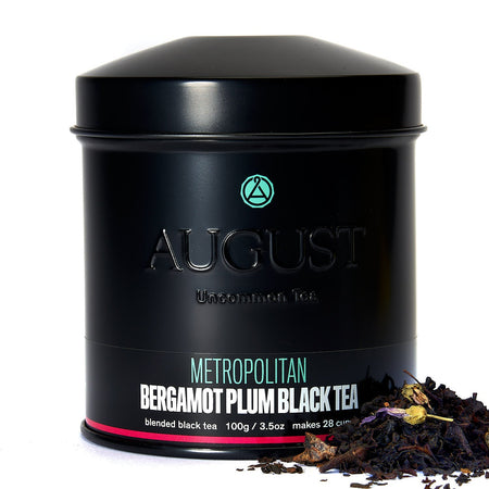 August Metropolitan - Bergamot Plum Earl Grey Black Tea leaves displayed in a tea setting with greenery.