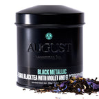 August Black Metallic - Violet Elderberry Black Tea in a sleek black tin packaging, displayed on a neutral background.