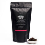 August Breakfast - Smoky Vanilla Black Tea in a bag, presented with a cup, showcasing its unique blend and packaging.