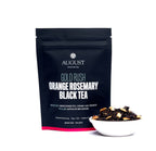 August Gold Rush - Orange Rosemary Caramel Black Tea in a tasting setup with cups and a notebook for tea sampling.