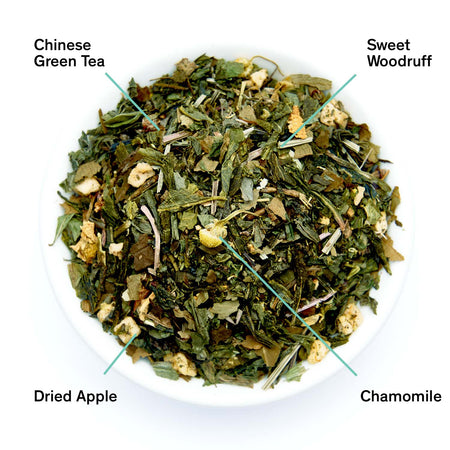 August Neon Forest - Sweet Woodruff Chamomile Green Tea in a cup, showcasing leaves and ingredients like sweet woodruff and chamomile.