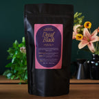 August Essentials Decaf Black Black Tea in a 70 cup bag, shown in packaging with tea leaves visible.