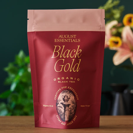 August Essentials Black Gold Black Tea in a cup, featuring organic Yunnan black tea with malty and caramel notes.