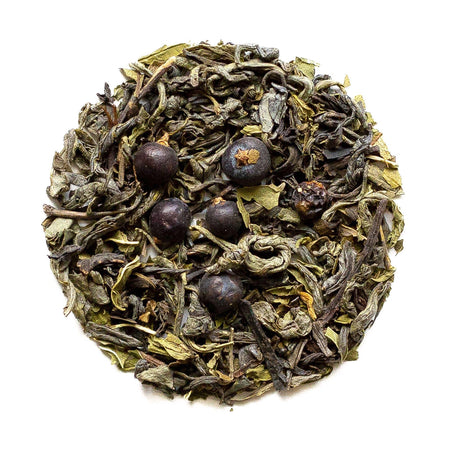 Beach House Haystack Green Tea leaves on a leafy background, showcasing the refreshing blend inspired by Oregon's coastline.
