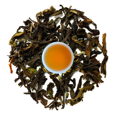 Danfe Himalayas Best Oolong Tea, loose leaf oolong tea leaves and brewed liquor displayed in a glass.