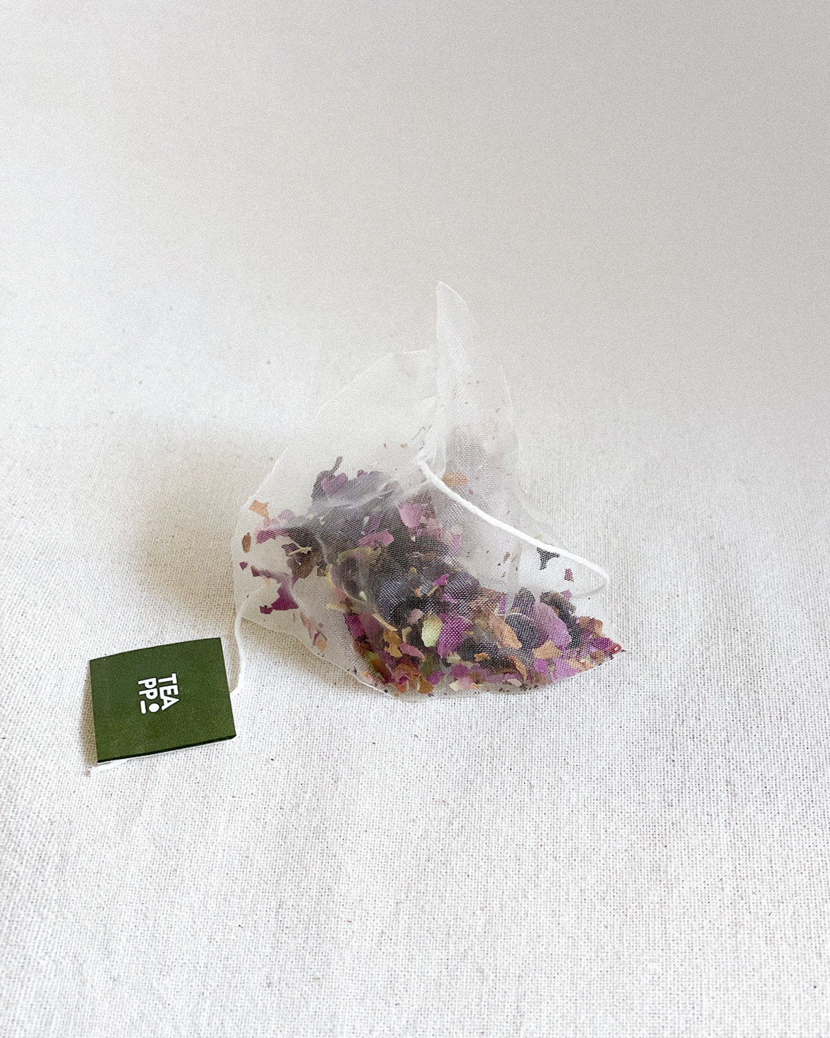 Teappo Rose Oolong tea leaves in a clear glass container, showcasing their color and texture