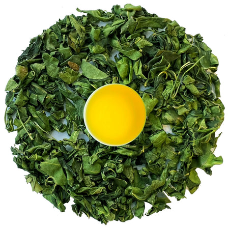 Danfe Himalayan Moringa Tea (Caffeine-Free Superfood Herbal Tea) in a clear cup with brewed tea and loose leaf moringa leaves.