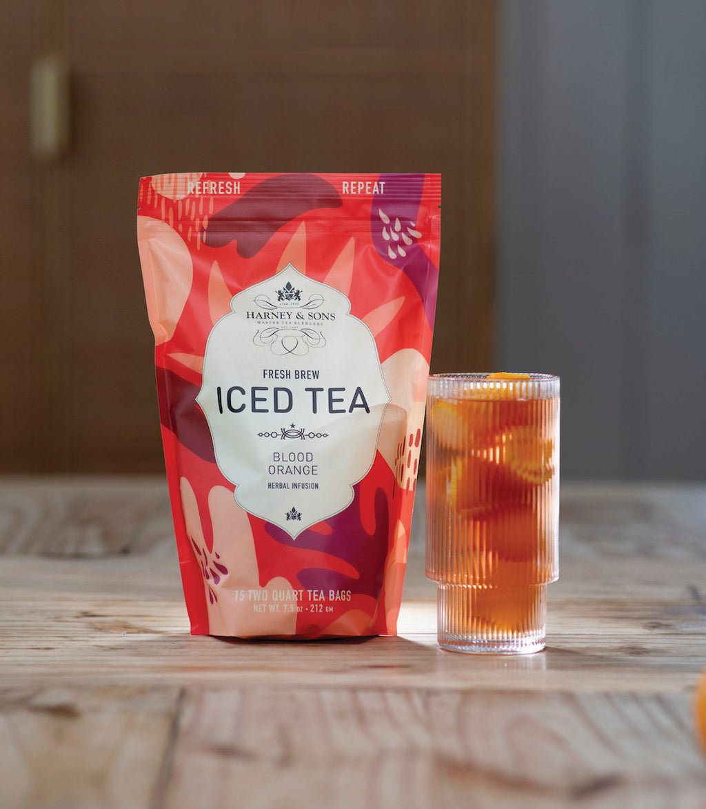 Harney & Sons Blood Orange Fresh Brew Iced Tea in a glass, featuring a vibrant orange color and citrus garnishes.