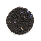Plum Deluxe Breakfast in Bed Black Tea (Blackberry - Hazelnut) in a circular packaging with blue cornflowers displayed.