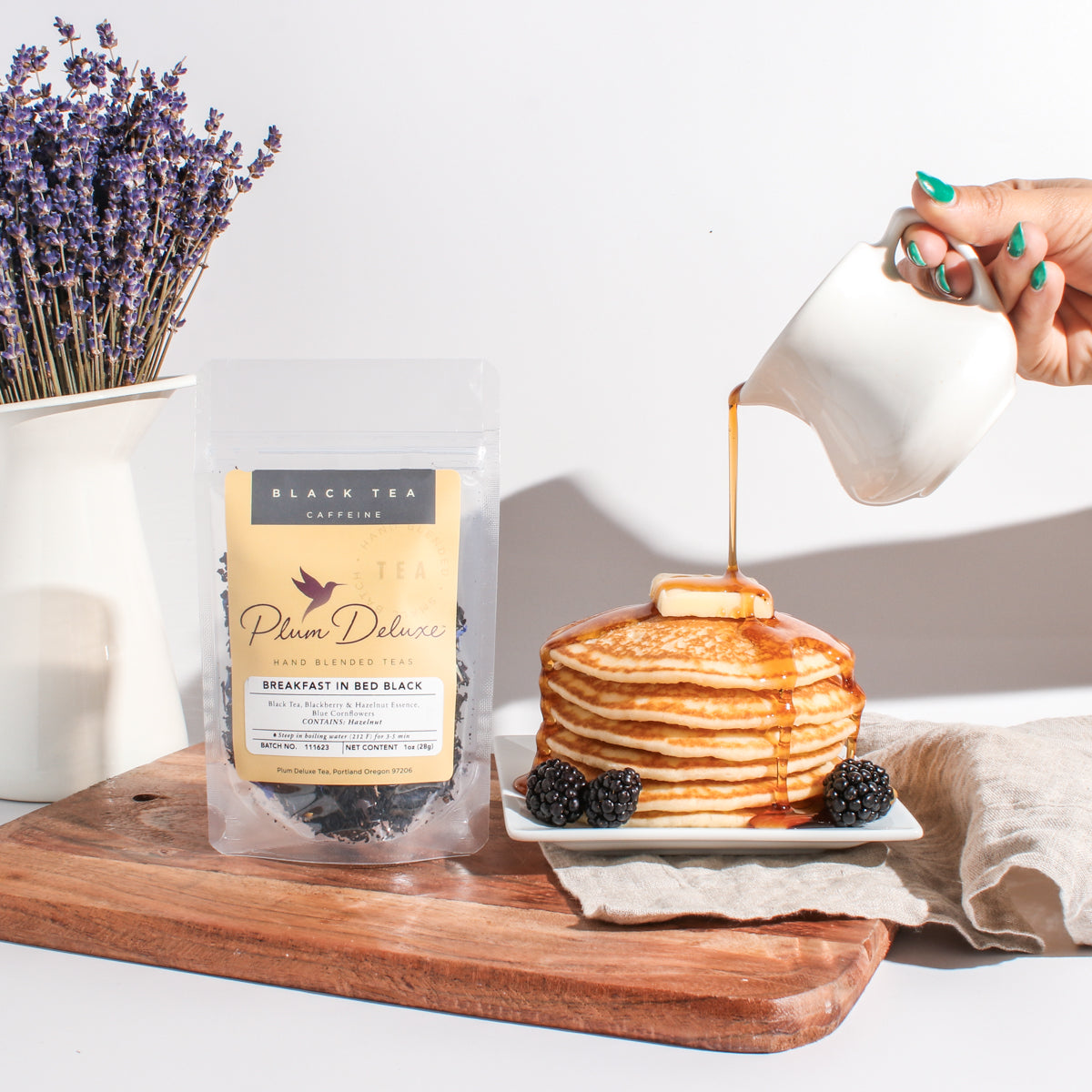 Plum Deluxe Breakfast in Bed Black Tea (Blackberry - Hazelnut) in a cozy lifestyle setting with tea cup and snacks.