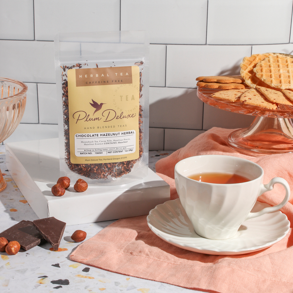 Plum Deluxe Chocolate Hazelnut Dessert Tea in a lifestyle setting, showing the tea packaging and a cup of brewed tea.