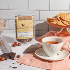 Plum Deluxe Chocolate Hazelnut Dessert Tea in a lifestyle setting, showing the tea packaging and a cup of brewed tea.