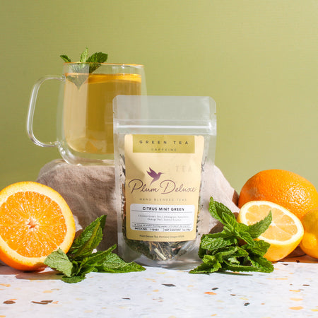 Plum Deluxe Citrus Mint Green Tea in a lifestyle setting, featuring lemon, orange, lemongrass, and mint.