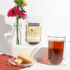 Plum Deluxe Comfort Blend Black Tea (Orange - Cinnamon) displayed in a lifestyle setting with tea accessories.
