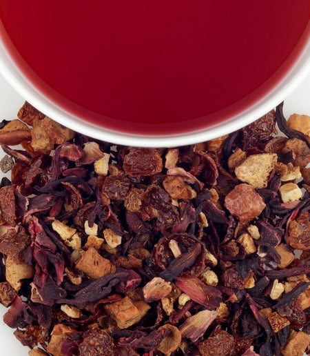 Harney & Sons Orange Passion Fruit Tea displayed in a cup, featuring dried oranges and tropical fruits in a ruby-red infusion.