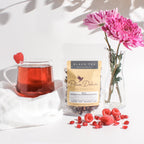 Plum Deluxe Wonder-Full Pomegranate Decaf Black Tea in a cup, with pomegranate and tea leaves displayed in a lifestyle setting.