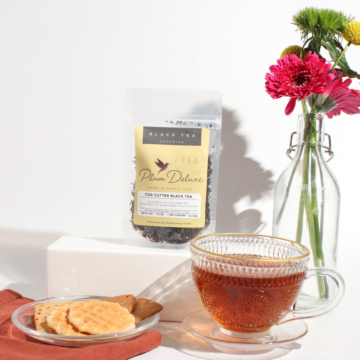 Plum Deluxe Fog Cutter Black Tea (Irish Breakfast w-Hint of Lemon) in a lifestyle setting, showcasing the tea package and cup.