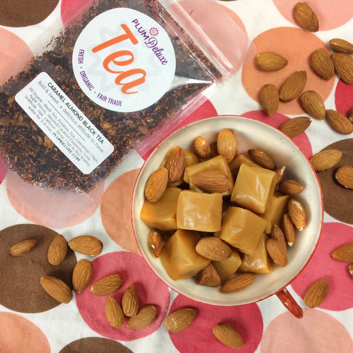Plum Deluxe Caramel Almond Black Tea in a loose leaf form displayed in a clear container on a wooden surface.