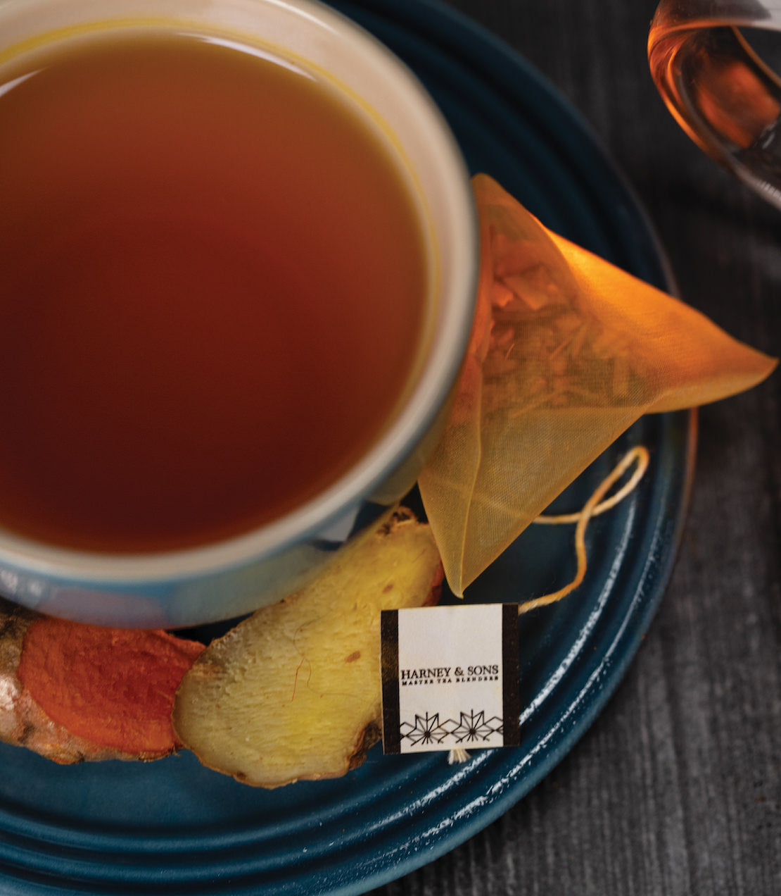 Harney & Sons Organic Ginger Turmeric HT Tin of 20 Sachets displayed in a mood setting with a rustic background.