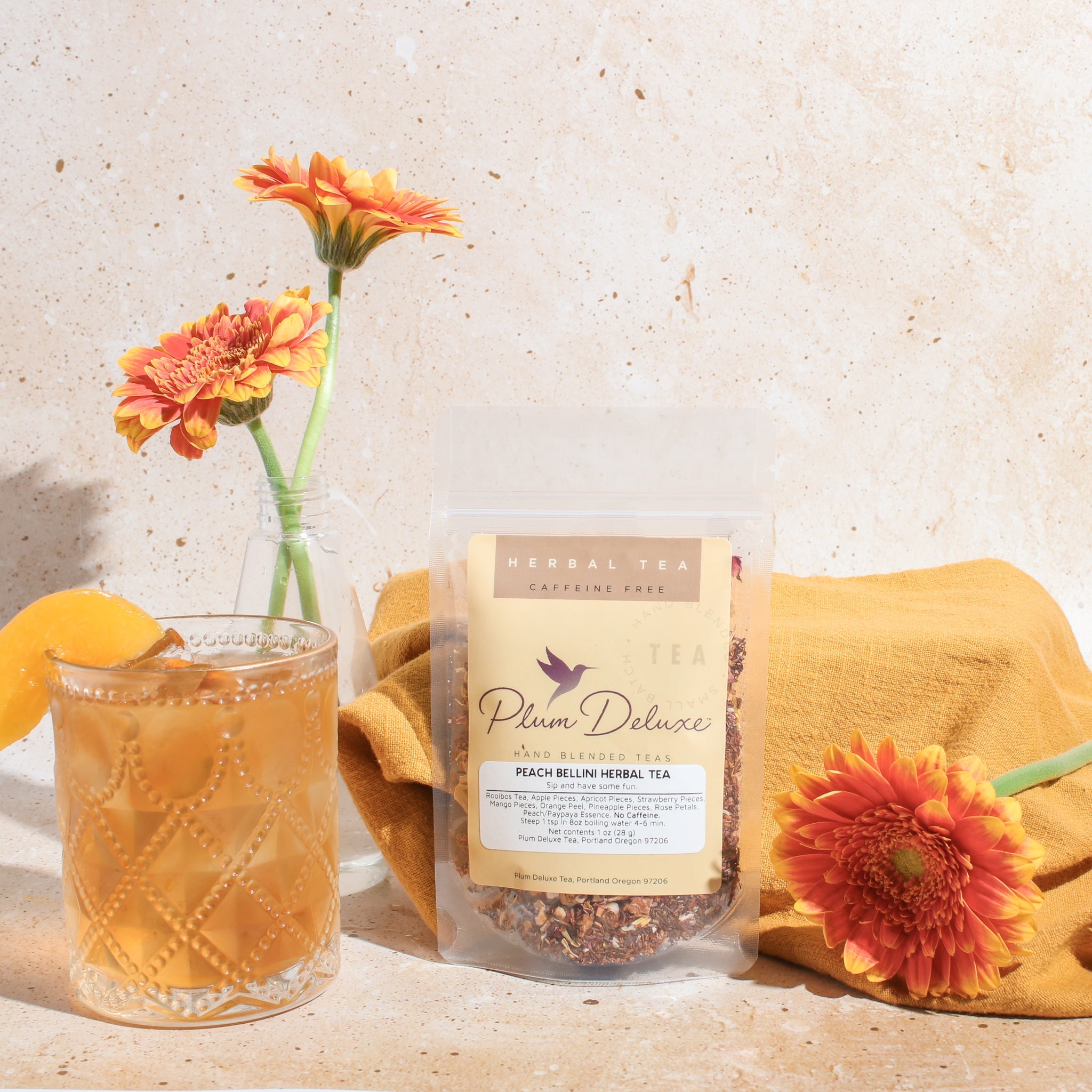 Plum Deluxe Peach Bellini Herbal Tea in a lifestyle setting, showcasing the tea's packaging and vibrant colors.