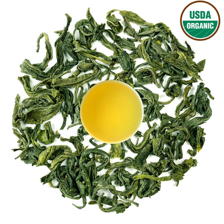 Danfe Mt. Pumori Best Green Tea (Certified Organic) loose leaf tea leaves with brewed liquid in a cup, showcasing its color and freshness.