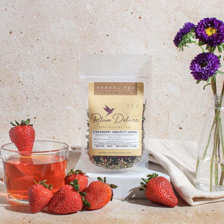 Plum Deluxe Strawberry Immunity Herbal Tea with berries and echinacea, shown in a lifestyle setting.