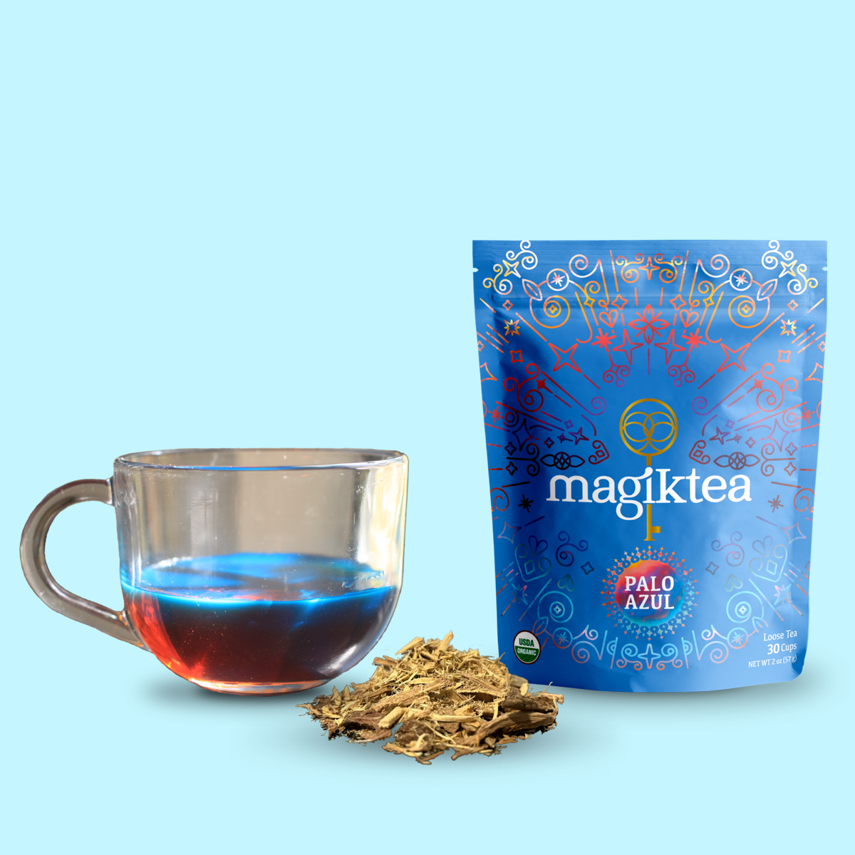 Magiktea Palo Azul tea packaging with a glass of tea and loose tea leaves on a light blue background