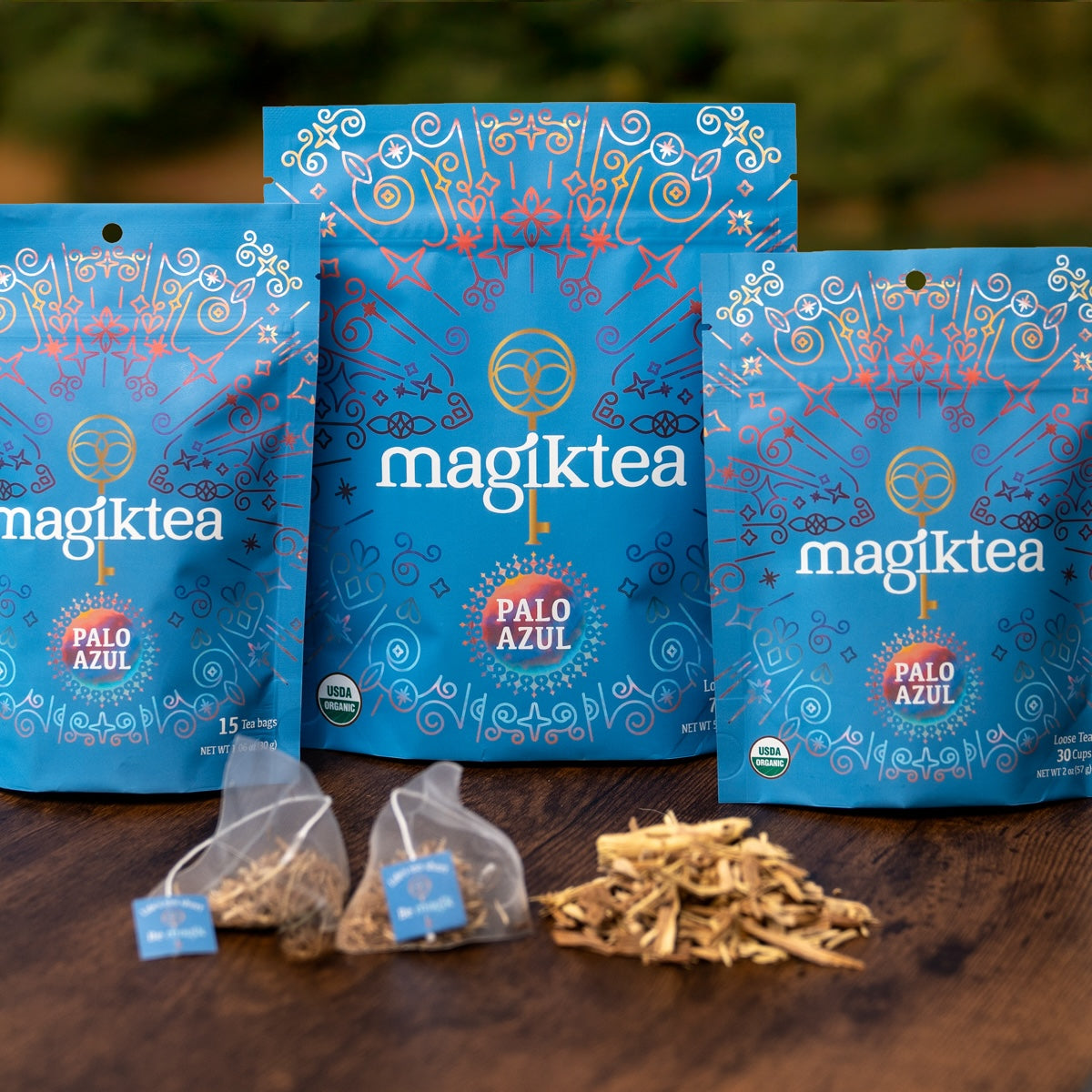 magiktea Palo Azul tea packages on a wooden surface with loose tea leaves.