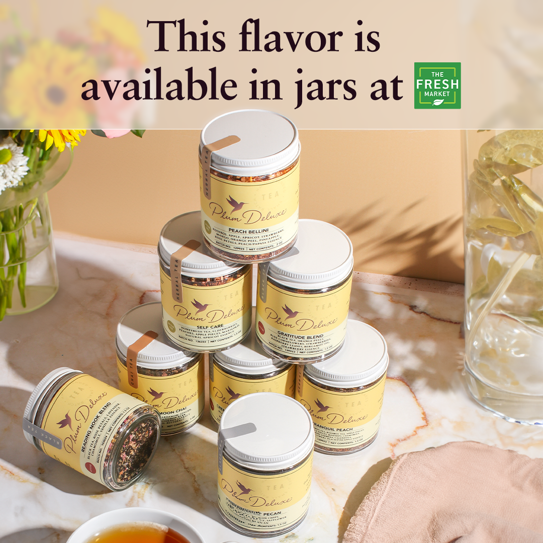 Plum Deluxe Peach Bellini Herbal Tea in a jar on a wooden surface, showcasing its vibrant color and packaging.